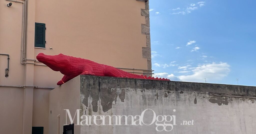 Il grosso coccodrillo rosso sul tetto di un garage