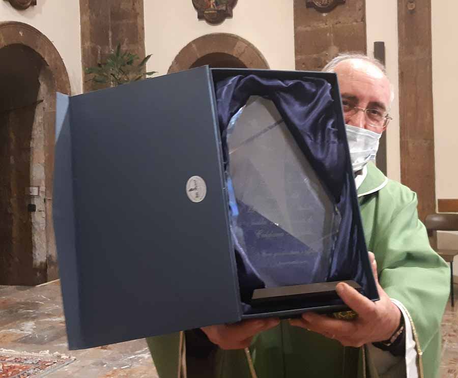 Don Enzo Mantiloni con la targa che la comunità di Caldana gli ha donato per i 50 anni di sacerdozio