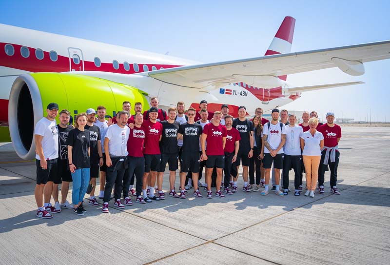 Luca Banchi con la nazionale della Lettonia di basket davanti all'aereo che li riporterà a Riga