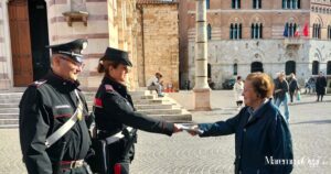 Due carabinieri consegnano ad una donna il decalogo per non cadere nelle truffe, in piazza del Duomo a Grosseto