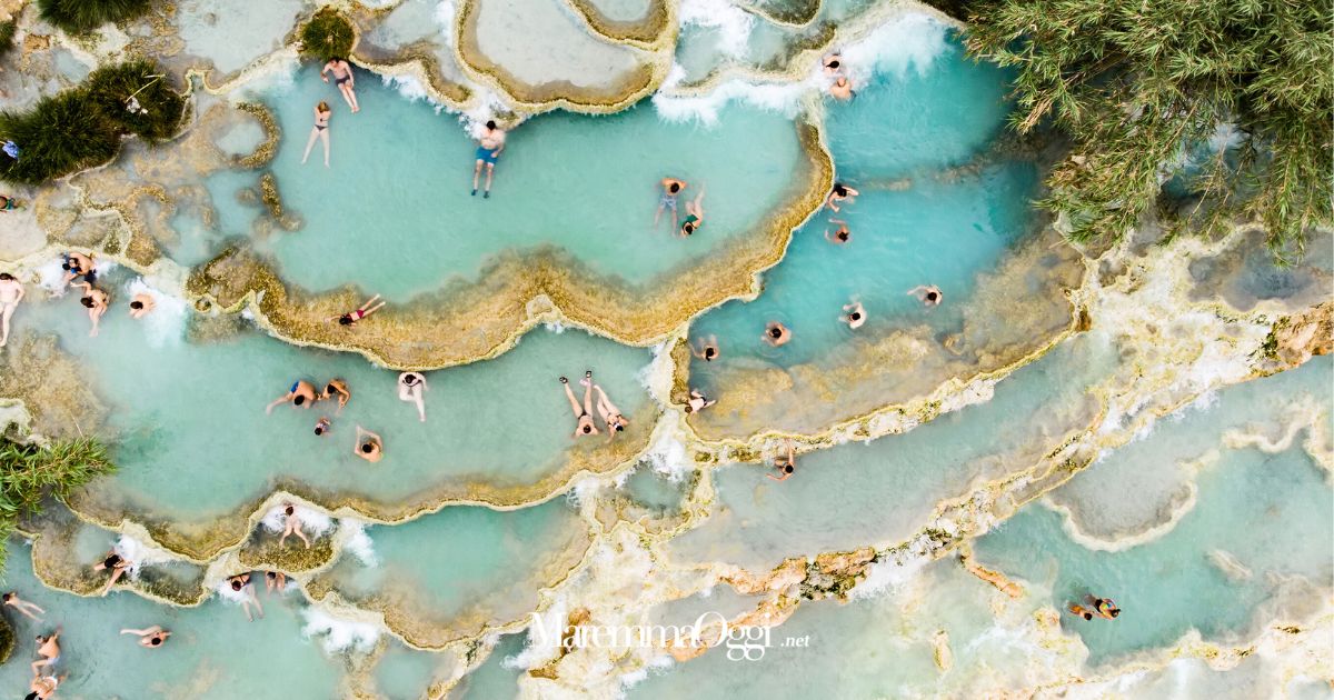 Turisti immersi nell'acqua termale alle cascatelle di Saturnia, in Maremma