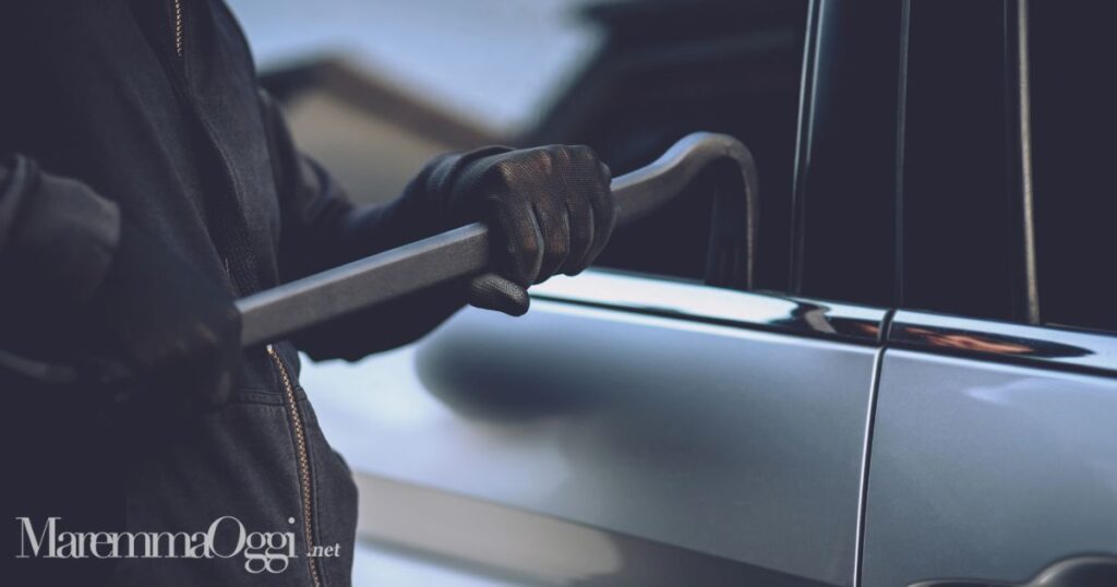 Un ladro che forza una portiera (foto d'archivio)