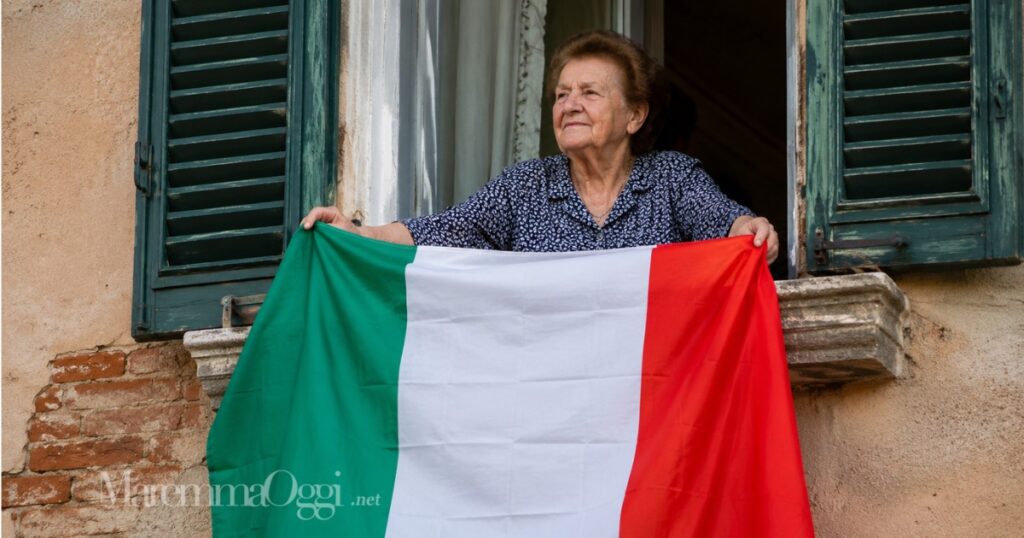 Una donna espone il tricolore alla finestra di casa