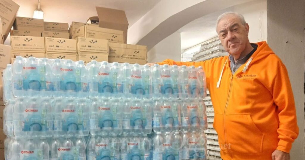 Don Enzo Capitani con le bottiglie d'acqua donate da Conad